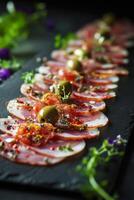 Deliciously arranged cured meats and olives on a dark slate platter for an elegant appetizer photo