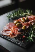 Deliciously arranged cured meats and olives on a dark slate platter for an elegant appetizer photo