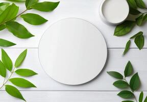 Circular white plate surrounded by vibrant green leaves on a light wooden surface photo