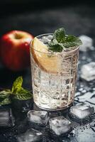 Refreshing drink with lemon and mint beside a fresh apple on a dark background photo