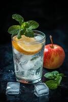 Refreshing drink with lemon and mint beside a fresh apple on a dark background photo