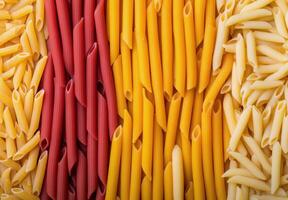 Dried yellow pasta pieces scattered on bright yellow background in a creative layout photo