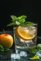Refreshing drink with lemon and mint beside a fresh apple on a dark background photo