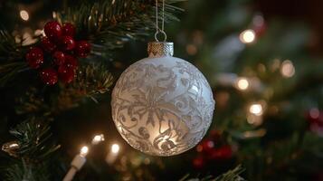 Elegant glass ornament hangs on Christmas tree branch with soft lighting photo