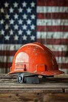 Hard hat placed on wooden surface with American flag as background in construction setting photo