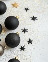 Decorative black and gold Christmas ornaments on a white background with glitter photo