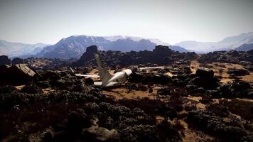 Plane crash site in rocky terrain with distant mountains at midday video