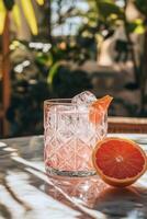 Refreshing grapefruit cocktail garnished with citrus slice in a bright outdoor setting photo