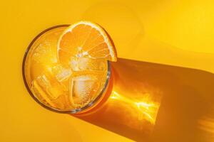 Orange Juice in a Glass with Ice and an Orange Slice on a Yellow Background photo