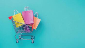 A Shopping Cart Filled with Colorful Paper Bags on a Turquoise Background photo