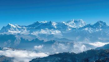 Snowy Mountain Range with Fog and Blue Sky photo