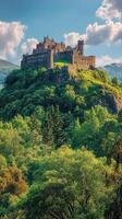 Historic castle perched on a hilltop surrounded by lush greenery under a blue sky photo