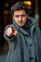 Confident man pointing directly at the camera on a bustling city street during the day photo