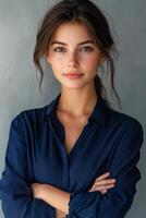 A confident woman poses with arms crossed against a neutral background in a casual setting photo