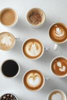 A variety of coffee cups with latte art displayed on a white surface in a cozy cafe setting photo