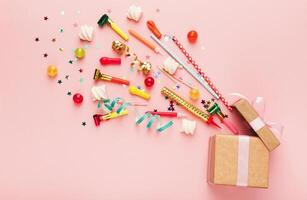 Birthday party background with gifts and firework of confetti, sweets on pink backdrop, copy space, top view. photo