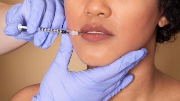 A professional performs a lip enhancement procedure on a client, using a syringe for injectable filler. The clinic environment is clean and focused on beauty treatments. photo