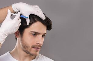 Man with hair loss problem receiving injection in head, grey background, empty space photo
