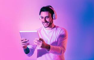 Online game concept. Handsome man with tablet and wireless headphones photo