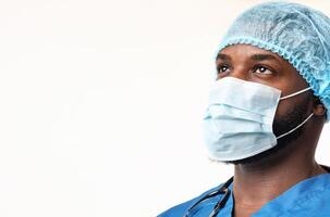 Ready to fight with covid-19. Young black male surgeon in mask and hair net looking at copy space over white background photo