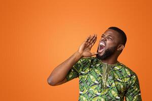 Attention. Emotional black guy in green shouting towards copy space over yellow background, panorama photo