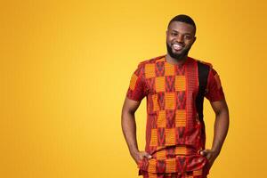 Smiling african guy in authentic clothes posing over yellow studio background photo