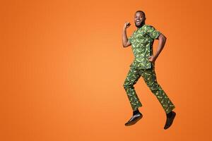 Joyful black man happily jumping up over yellow studio background photo