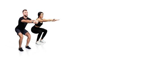 Two fitness enthusiasts perform synchronized squats in a workout setting. They focus on proper form and technique while engaging in a strength training routine. photo