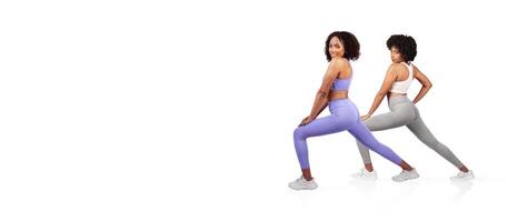 Two women perform athletic poses, highlighting their strength and flexibility. They wear stylish workout attire while positioned against a plain background, emphasizing their focus and determination. photo