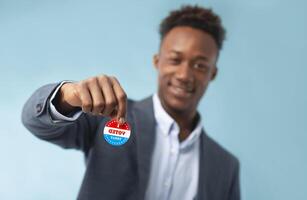 Close up of patriotic campaign button in hand of african american businessman voter, elections in USA 2020, blurred background photo