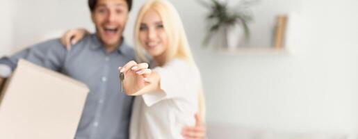 Home Owners. Excited Couple Showing Keys Hugging In New House. Shallow Depth, Selective Focus, Copy Space photo