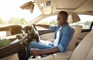 Happy black guy in casual driving car, inside shot, copy space photo