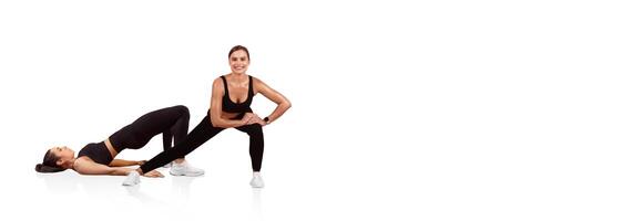 Two women engage in a challenging fitness routine, one in a bridge position and the other assisting with resistance. They are focused and energetic, demonstrating teamwork in their workout. photo