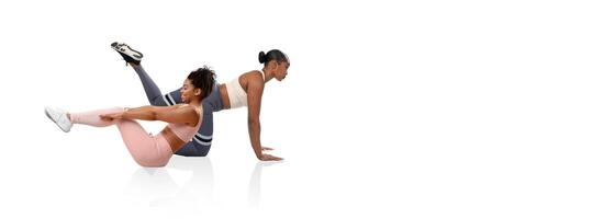 Two women perform a challenging workout routine in a fitness studio. One woman demonstrates a core exercise while the other focuses on maintaining her balance and strength. photo