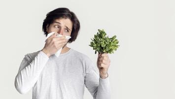 Man fighting with spring allergies and covers his nose with napkin photo