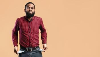 Poverty And Absence Of Money Concept. Unemployed sad black man showing empty pockets, isolated on yellow studio wall photo