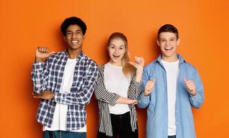 Diverse classmates pointing fingers at themselves, posing to camera over orange studio background photo