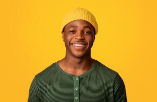 Portrait Of Cheerful Young African American Guy In Orange Hat Smiling At Camera, Happy Millennial Male Having Fun While Posing Over Yellow Background In Studio, Closeup Shot With Free Space photo