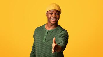Nice To Meet You. Cheerful Black Guy Extending Hand For Handshake At Camera, Positive Friendly Millennial African American Man Greeting Somebody While Standing Over Yellow Studio Background photo