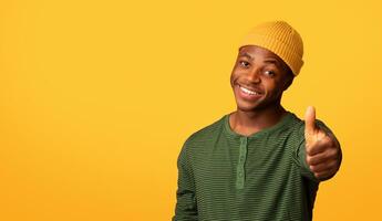 Great Choice. Positive African American Hipster Guy Showing Thumb Up At Camera, Cheerful Black Millennial Man , Recommending Something, Gesturing Sign Of Approval While Posing Over Yellow Background photo