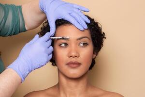 A woman with curly hair receives a cosmetic injection being administered by a specialist. The setting is calm, with soft lighting creating a soothing ambiance during the procedure. photo