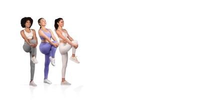 Three women in athletic wear are engaging in dynamic leg stretches, highlighting fitness and teamwork in a bright studio setting, promoting health and exercise awareness. photo