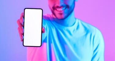 Smiling man shows to camera smartphone with blank screen, cropped photo