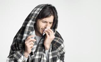 Sick man with in blanket napkin and drops for nose in hands, empty space photo