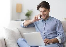 Always in touch. Successful entrepreneur talking on cellphone working at laptop sitting on sofa at home. Empty space photo