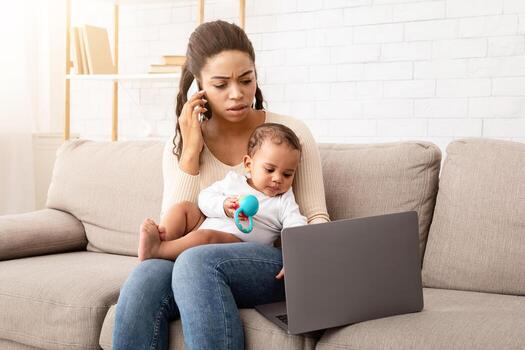 negro madre multitarea cuidando para bebé, hablando en teléfono y utilizando ordenador portátil sentado en sofá a hogar. africano americano persona de libre dedicación mamá trabajando remotamente durante maternidad salir. maternidad concepto foto