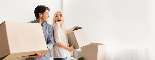 Excited Spouses Carrying Moving Boxes Smiling Looking At Each Other Leaving Old Flat. Free Space photo
