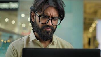 Stressed upset Indian Muslim bearded man in glasses talk call has problem with laptop business failure overworked with computer work lost job bankruptcy. Arabian businessman overwhelmed stress photo