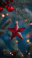 Decorative red star ornament hanging on a Christmas tree with twinkling lights at night photo