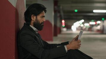 Worried stressed indian man using laptop in underground parking reading bad news on social media frustrated sad jobless arabian businessman looking for job on internet experiencing financial problems photo